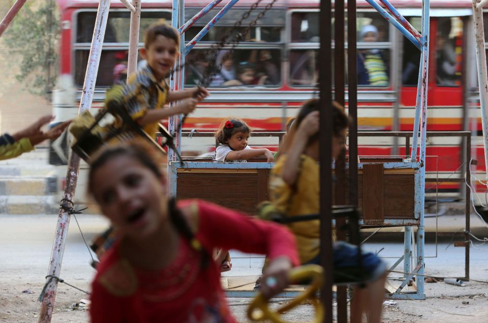 Syrian children play on swings in the Sy