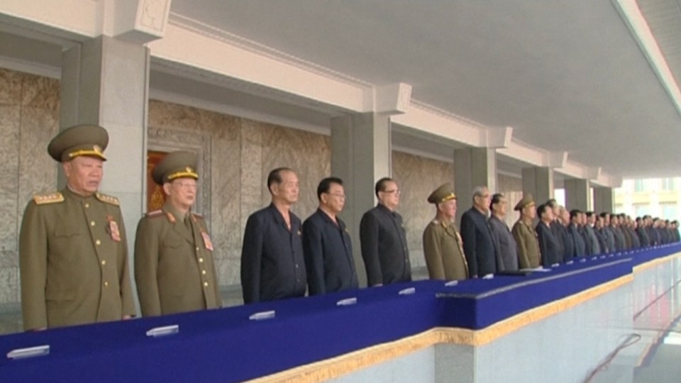 Party leaders stand on a balcony looking down on the crowd