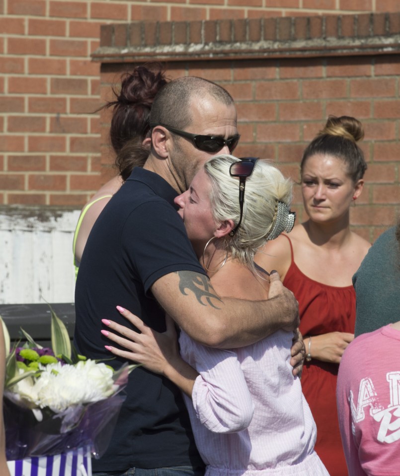Ricky's sister April is comforted as she looks at floral tributes left at the scene