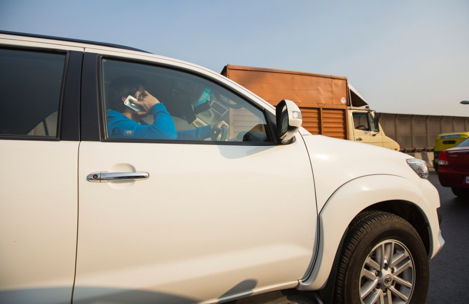 An Indian man driving a car in Delhi, India, whilst talking on his mobile phone.