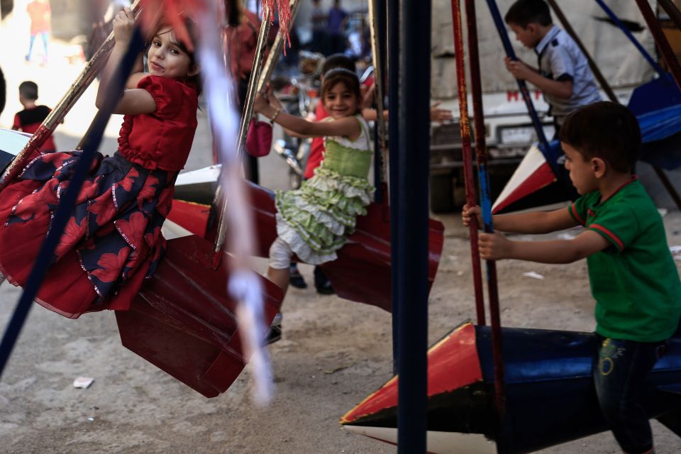 Syrian children play on swings, made fro
