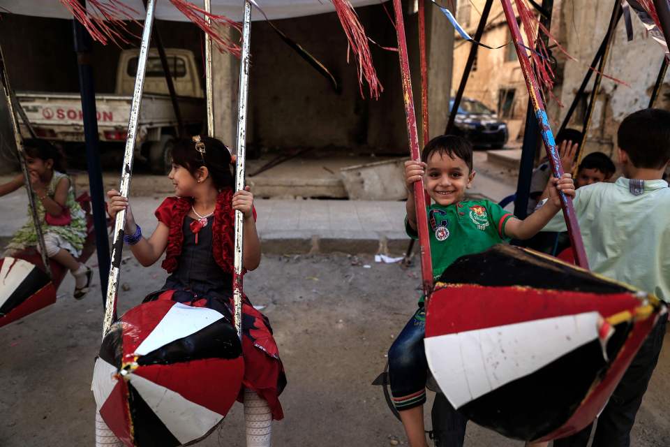 Syrian children play on swings, made fro