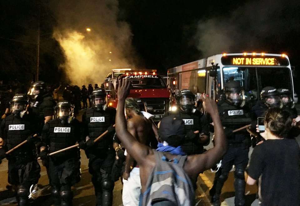 Police officers wearing riot gear block a road during protests after police fatally shot a man in the parking lot of an apartment complex in Charlotte