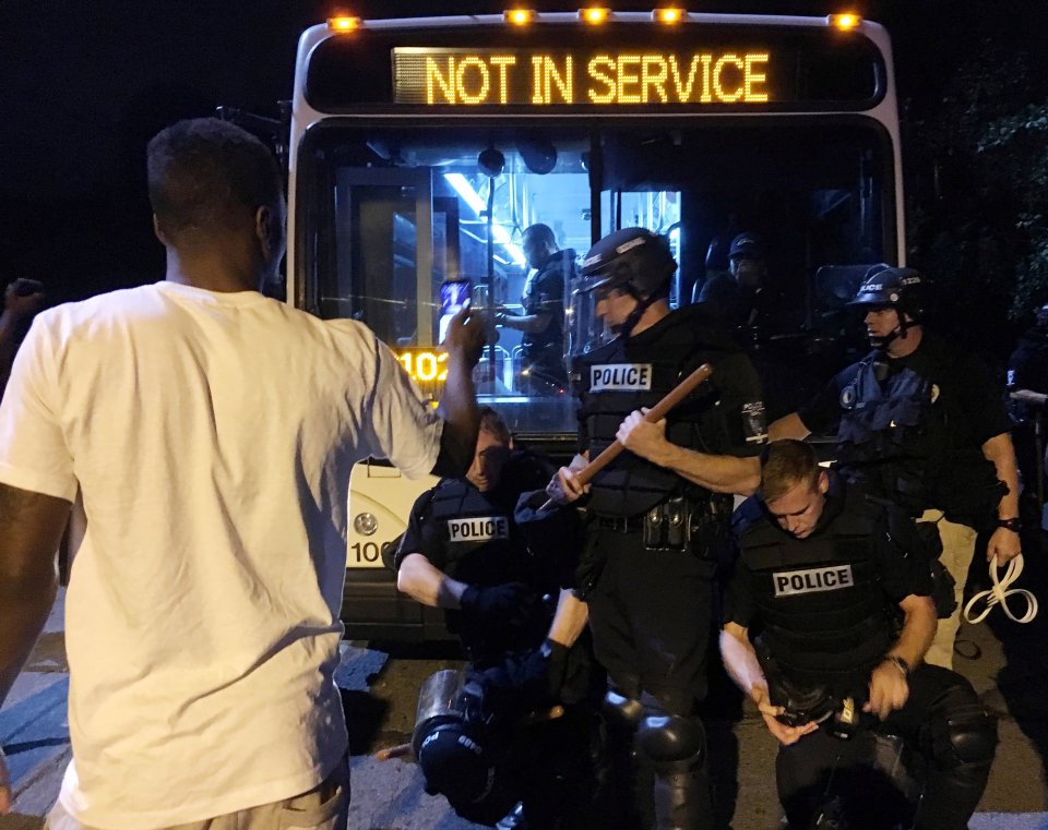 Police officers wearing riot gear block a road during protests after police fatally shot a man in the parking lot of an apartment complex in Charlotte