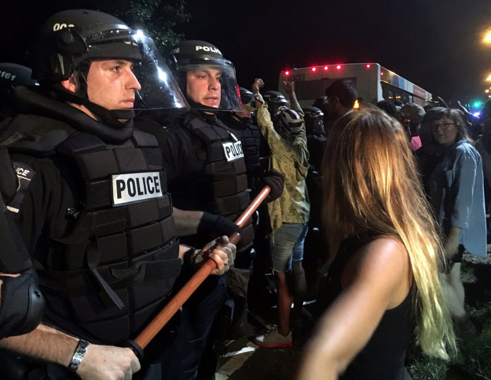 Police officers wearing riot gear block a road during protests after police fatally shot a man in the parking lot of an apartment complex in Charlotte
