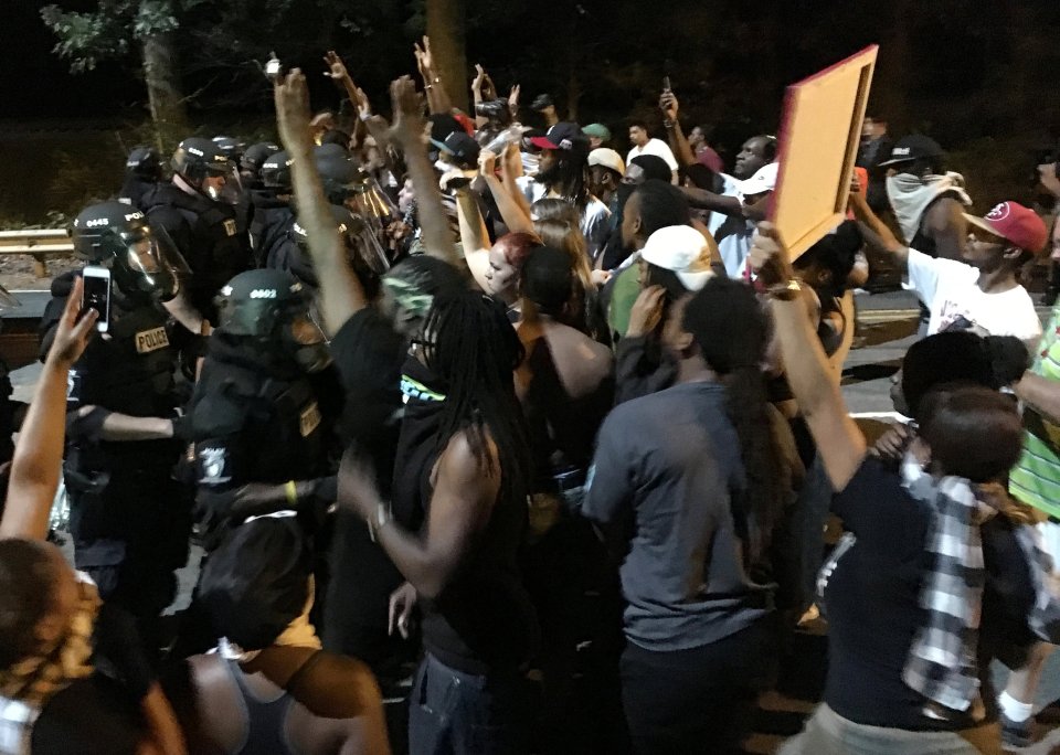 Protestors demonstrate in front of police officers wearing riot gear after police fatally shot Keith Lamont Scott in the parking lot of an apartment complex in Charlotte