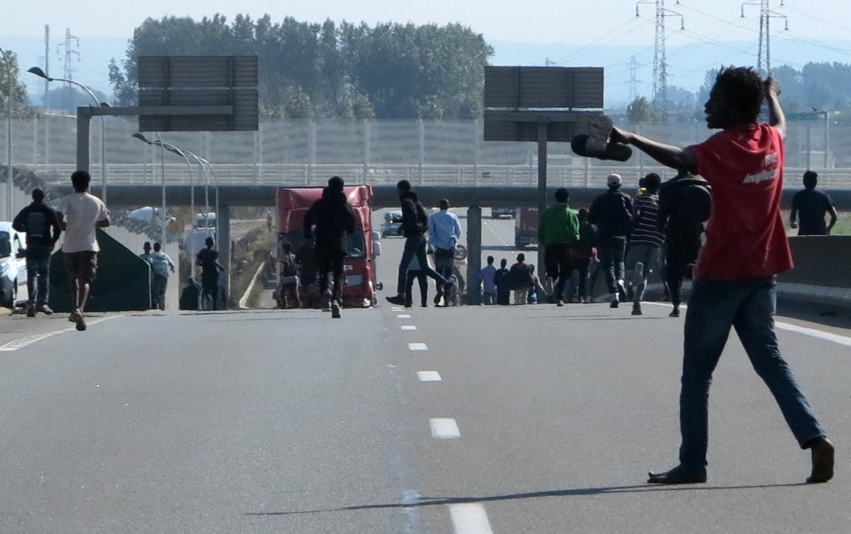 Dozens of migrants gather near lorries heading for the UK