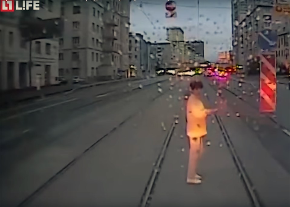 The woman suddenly comes into focus as the tram travels along the road