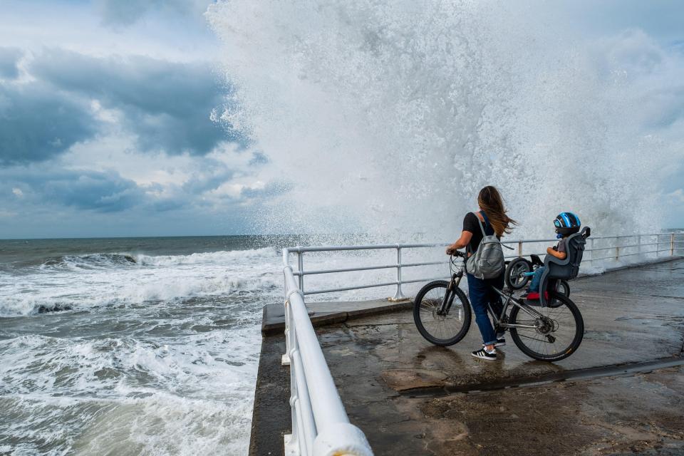 Aberystwyth Wales UK, Saturday 24 September 2016 UK Weather: A young mother and her child on their bike watch as blustery winds bring waves crashing along Aberystwyth seafront . photo ¿ Keith Morris / Alamy Live News