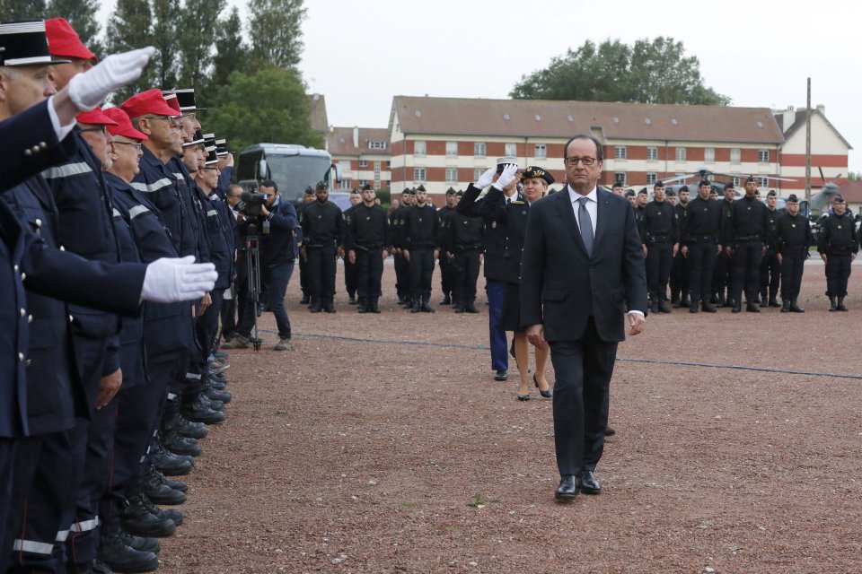 Hollande, seen striding through an inspection with officers, has vowed to close the Calais Jungle