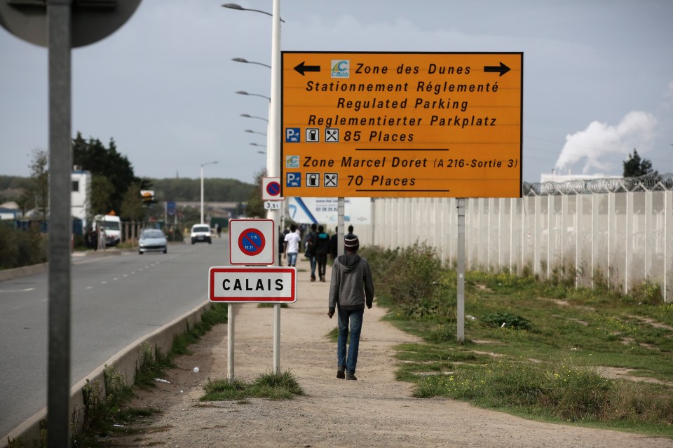 A migrant walks outside the makeshift camp on Monday