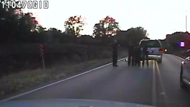 He is seen here lying on the floor after being tasered and shot - three male officers have surrounded him