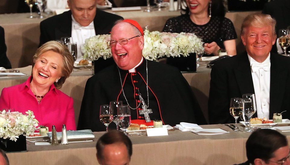 NEW YORK, NY - OCTOBER 20: Sitting between Cardinal Timothy Dolan, Hillary Clinton and Donald Trump attend the annual Alfred E. Smith Memorial Foundation Dinner at the Waldorf Astoria on October 20, 2016 in New York City.The white-tie dinner, which benefits Catholic charities and celebrates former Governor of New York Al Smith, has been attended by presidential candidates since 1960 and gives the candidates an opportunity to poke fun at themselves and each other. (Photo by Spencer Platt/Getty Images)