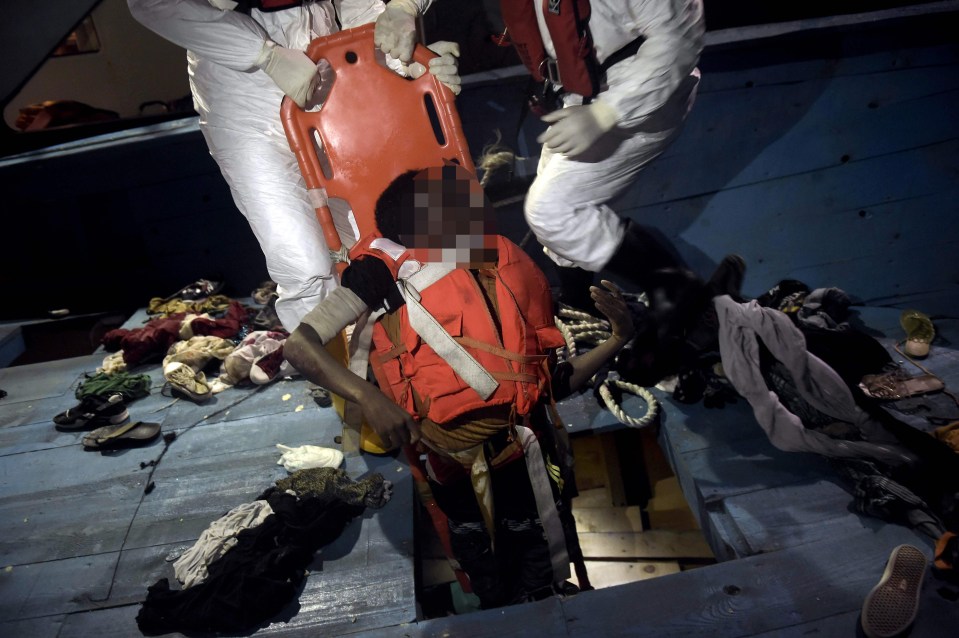 EDITORS NOTE: Graphic content / Members of Proactiva Open Arms NGO evacuate a dead body on a stretcher from the third level of a wooden vessel during a rescuing operation in the Mediterranean Sea, some 12 nautical miles north of Libya, on October 4, 2016. At least 1,800 migrants were rescued off the Libyan coast, the Italian coastguard announced, adding that similar operations were underway around 15 other overloaded vessels. / AFP PHOTO / ARIS MESSINISARIS MESSINIS/AFP/Getty Images 