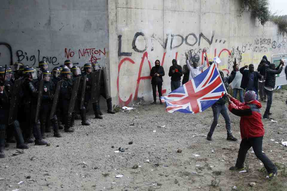 Demonstrators face off with French riot police as they protest near the area called the "jungle" where migrants live in Calais
