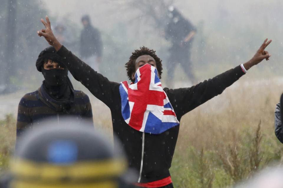 A migrant reacts near French riot police 