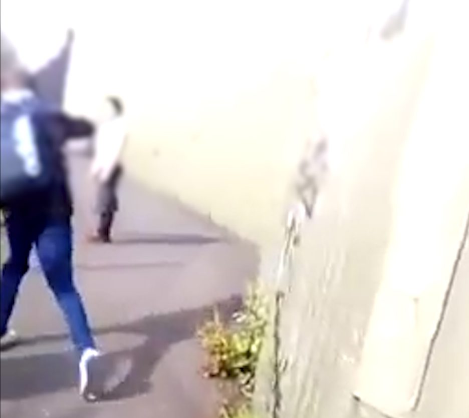 At one point, one is seen apparently throwing a stone at the woman