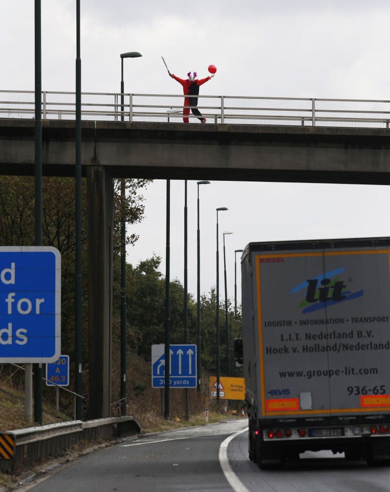 FAMEFLYNET - Exclusive: The Killer Clown Craze Shows No Sign Of Slowing Down As An Individual Dressed As A Clown Brandishing A Sword Is Seen On A Bridge Taunting Traffic Below On The M20