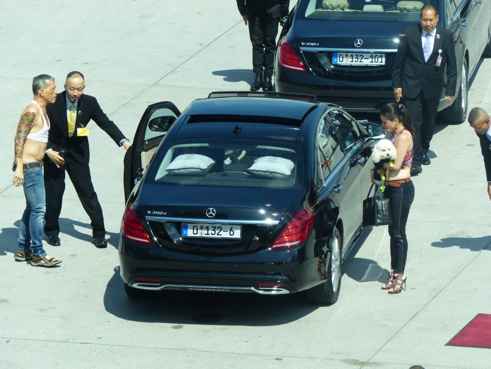 Maha Vajiralongkorn (far left) is seen at a Munich airport with a poodle and wearing a crop top