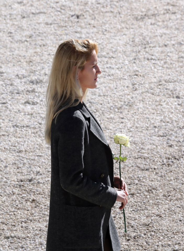 A woman holds a white rose during a nati
