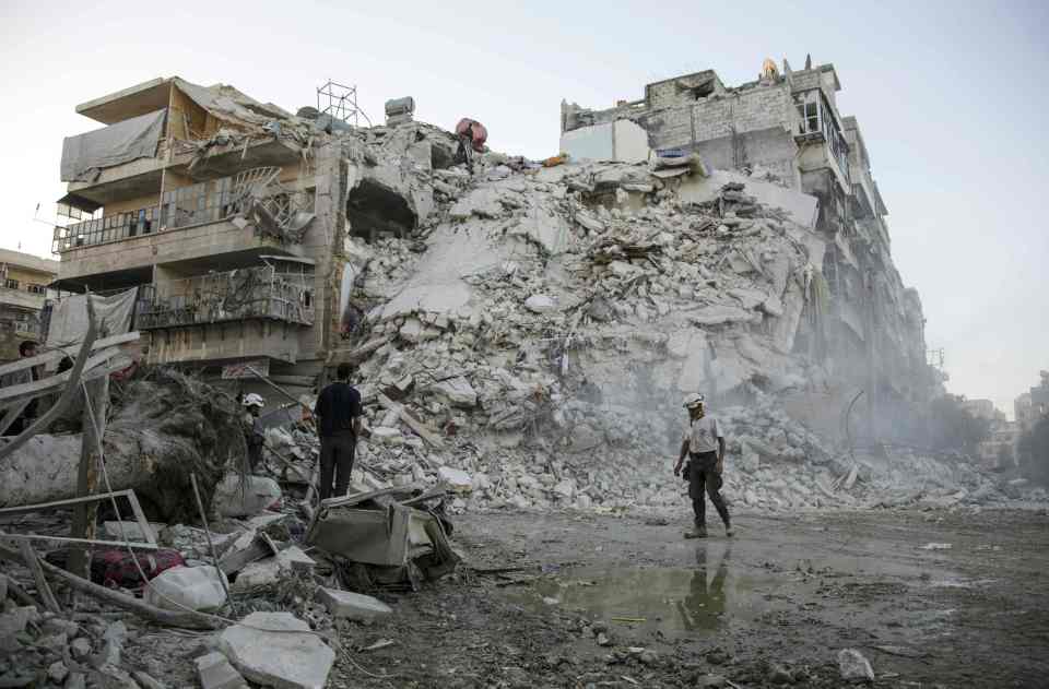 Members of the Syrian Civil Defence, known as the White Helmets, search for victims amid the rubble of a destroyed building following reported air strikes in the rebel-held Qatarji neighbourhood of the northern city of Aleppo by Russian planes