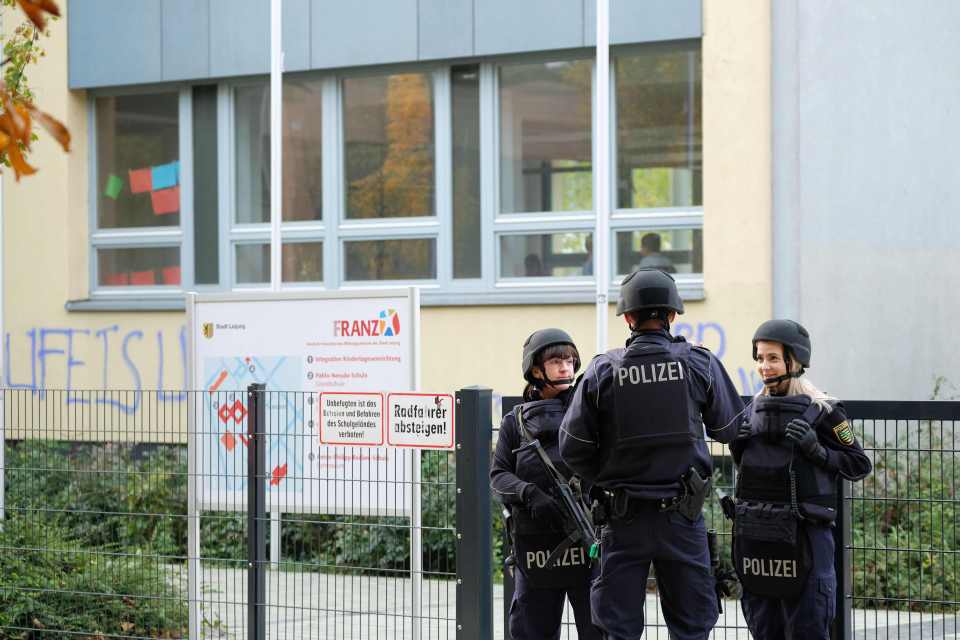 A group of police officers stand guard outside one of the school's threatened via email