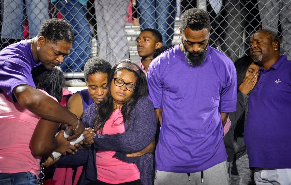 Shoshana Boyd (center left) and Olympic sprinter Tyson Gay (center right) stand surrounded by family and friends during a candlelight vigil at Lafayette High School for their daughter Trinity Gay