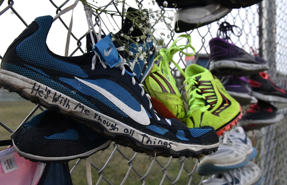 Pairs of track shoes are left on the fence at the entrance to a candlelight vigil for Trinity Gay