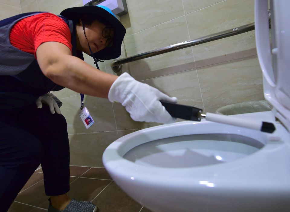 A member of Seoul's "hidden camera-hunting" squad waving a hand-held detector around the toilet seat 