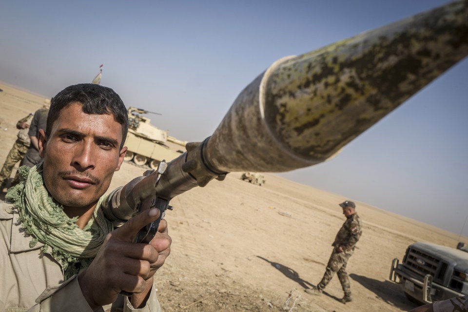 A soldier stands by as Iraq army tanks are refuelled before the next battle