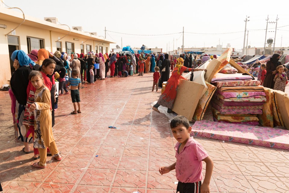 Women and children await aid at the Debaga camp