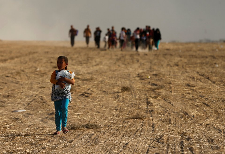 A lonely child in front of families returning to their villages after they were liberated from the Islamic State