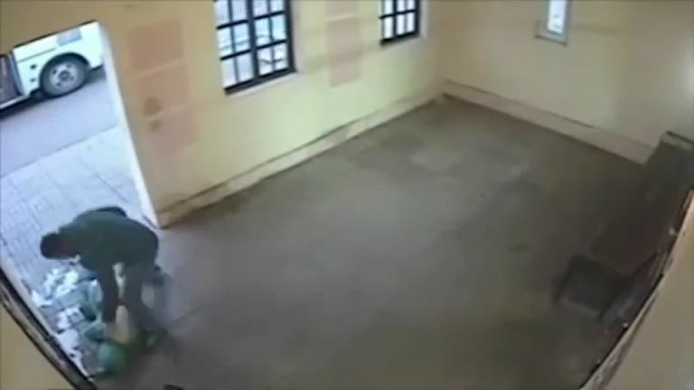He looms over the cowering and injured woman