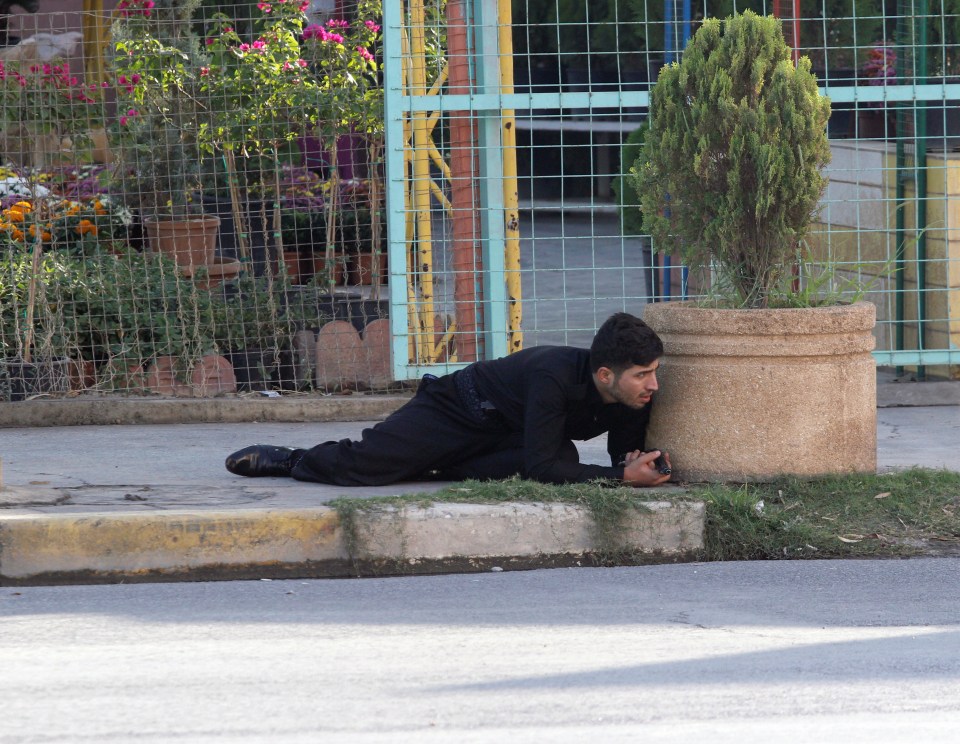 A Kurdish security personnel takes cover at a site of an attack by Islamic State militants in Kirkuk