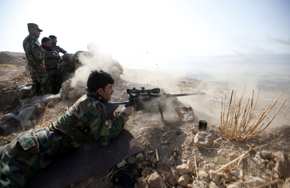 A Kurdish peshmerga fighter opens fire on ISIS militants in the town of Naweran, near Mosul