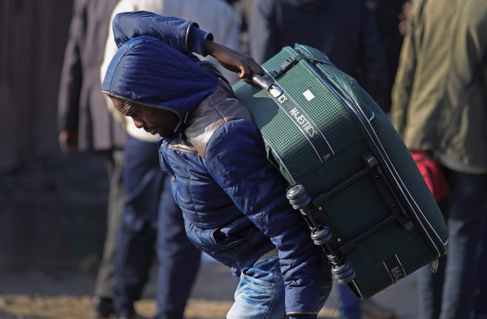 A migrant struggles with his bag as authorities move into demolish the jungle