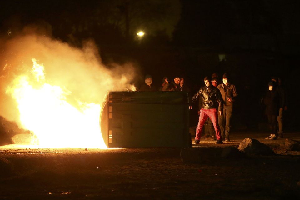 Migrants torched cars last night as they protested against the camp being demolished
