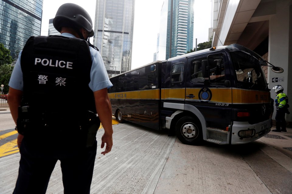Armed policemen guard the entrance as a prison car carrying British former banker Rurik Jutting enters High Court 