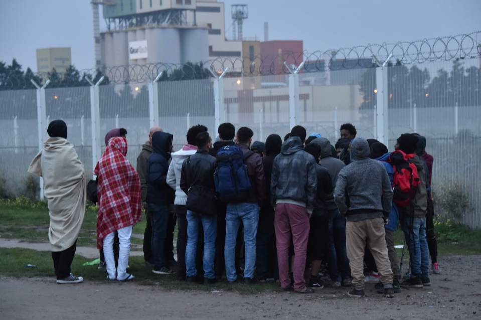 Migrants listen to an official during the full evacuation of the Calais 