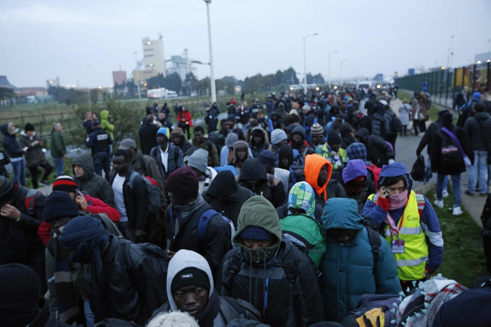 Migrants line-up to register at a processing centre set up by French authorities