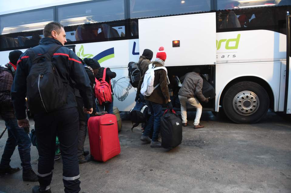 Migrants board buses for transportation to reception centres across France