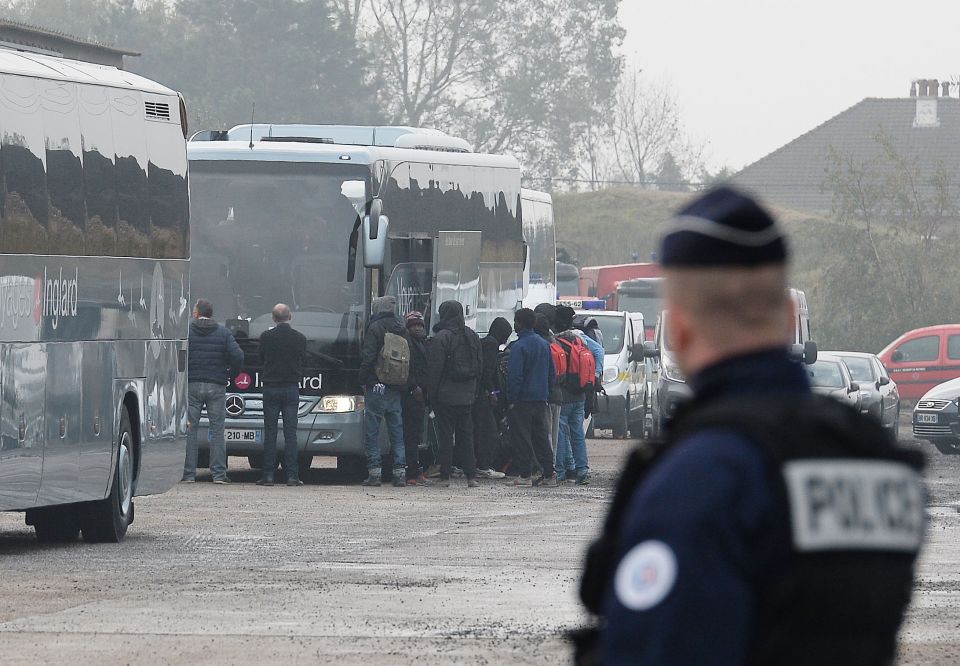 Migrants board buses after registering at a processing centre