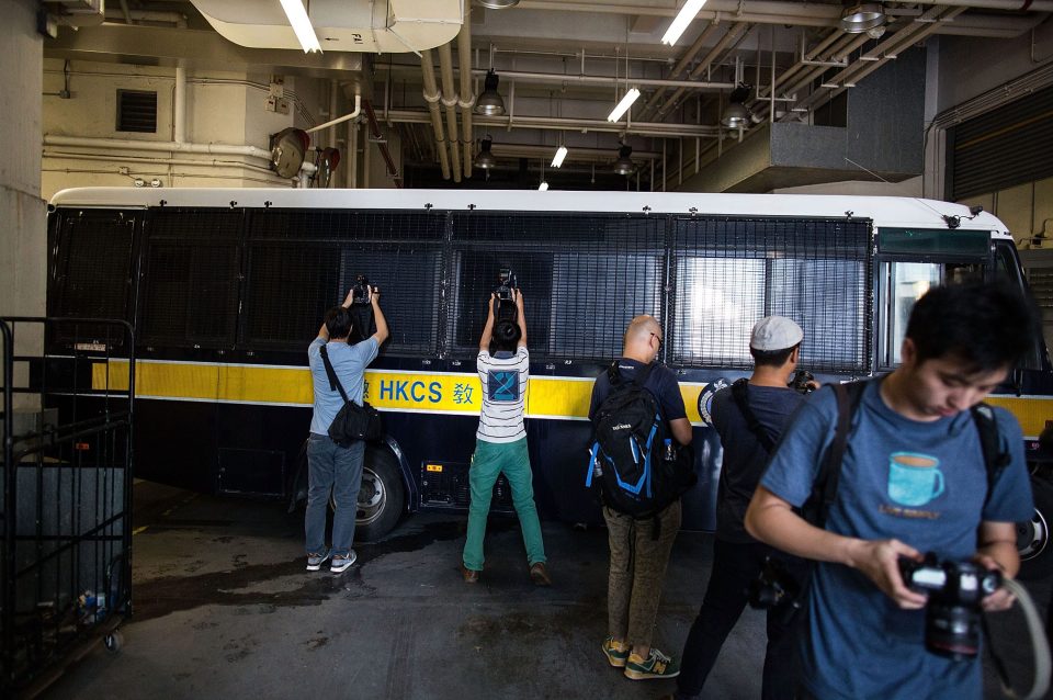 Photographers try to snap pictures of Jutting through the van's windows as it leaves court yesterday