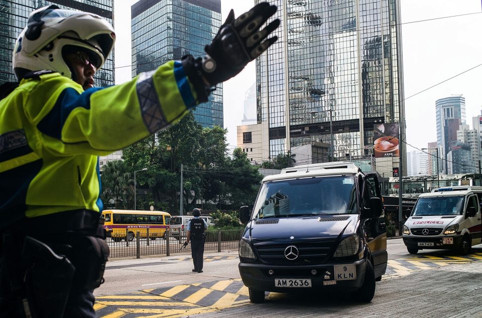A motorbike officer directs the van into the court building before the trial continued today