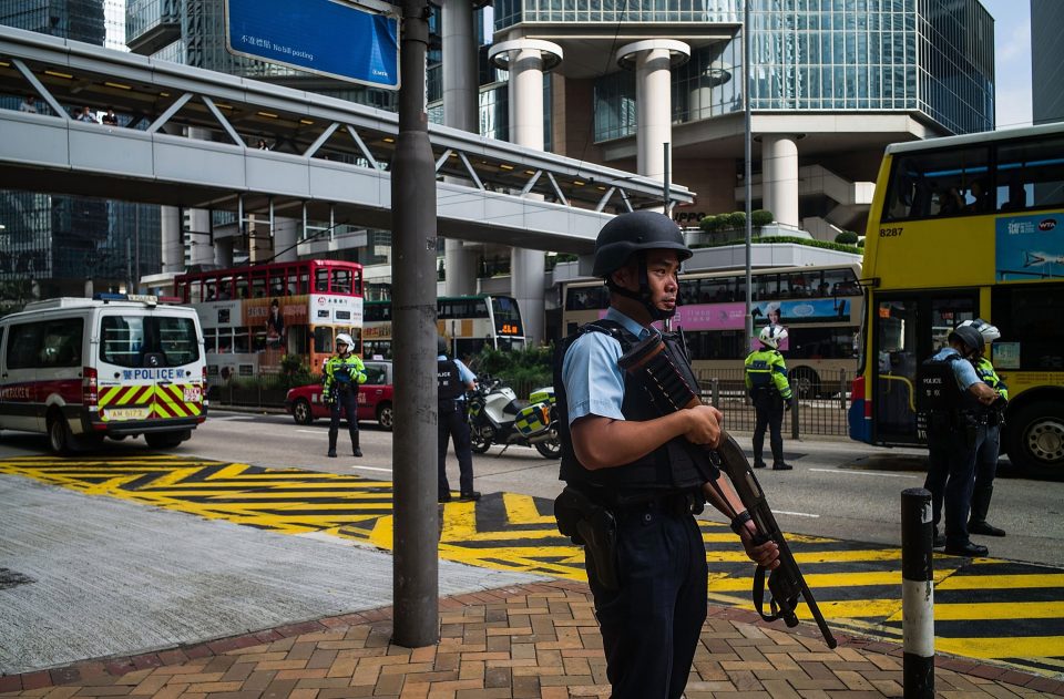Police officers stand guard as a prison vehicle escorting Rurik Jutting leaves court