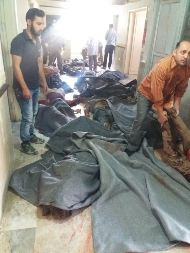 Rescuers cover bodies of adults and children killed in bomb attack on UK-funded schools in the Idlib province of Northern Syria