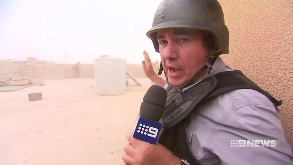 Aussie news reporter Mark Burrows casually carries on reporting as an intense firefight takes place behind him