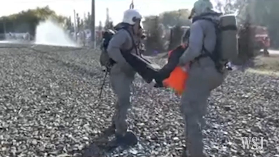 Soldiers dressed in hazchem gear carry victims of an attack away from the scene