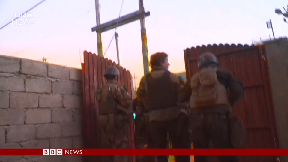 Footage shows soldiers standing in the back yard of a house talking