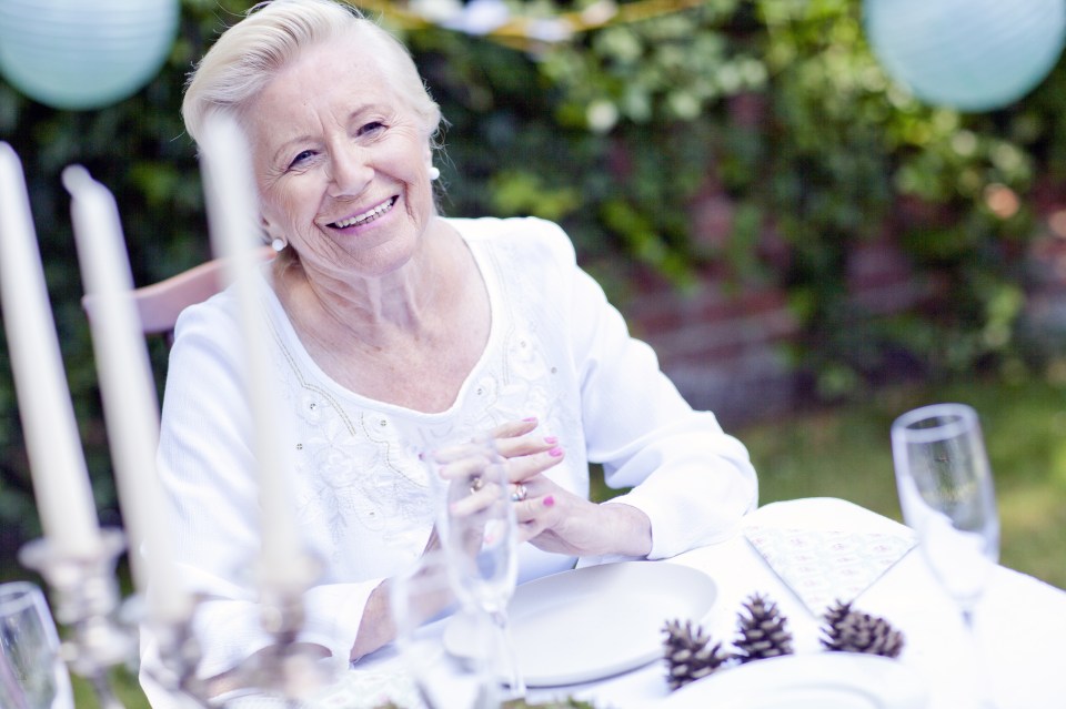 Portrait of senior woman sitting at table for garden party